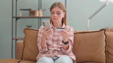 Genç Kadın Evdeki Kanepede otururken İnternetten Telefonla Alışveriş Yapıyor