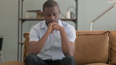 Baş ağrısı olan Afrikalı adam evdeki koltukta oturuyor.
