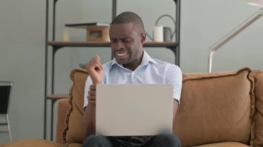 Evde dizüstü bilgisayar kullanan bilek ağrısı olan Afrikalı adam.