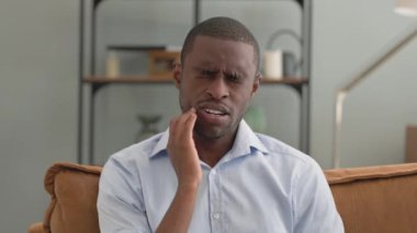 Dişi ağrılı Afrikalı bir adamın portresi Evdeki koltukta oturuyor