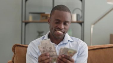Afrikalı Adam Evdeki Koltukta otururken Para Sayıyor