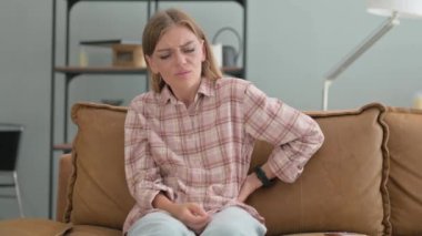 Sırtı ağrıyan genç kadın evdeki koltukta oturuyor.