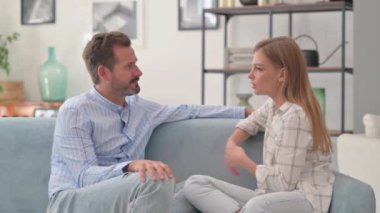 Genç çift evde kanepede otururken konuşuyor