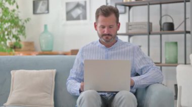 Orta yaşlı adam laptopta çalışıyor.