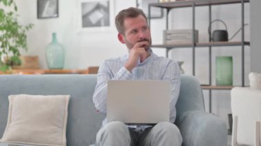 Laptop 'ta çalışan dalgın orta yaşlı adam.
