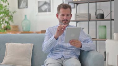 Orta Yaşlı Adam Tablet 'te Evdeki Koltukta Otururken Kazandı