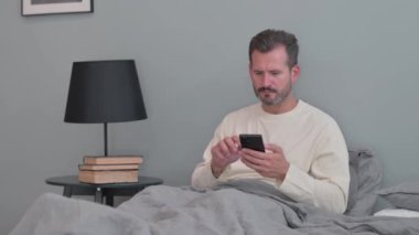 Yatakta Telefonda Konuşan Orta Yaşlı Adam