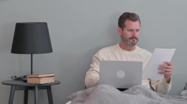 Evde Yatakta Belgeler Üzerinde Çalışan Orta Yaşlı Adam