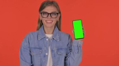 Turuncu Arkaplanda Yeşil Ekranlı Sıradan Genç Kadın Akıllı Telefon Gösteriyor