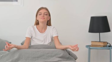 Yatakta otururken Yoga Yapan Genç Kadın