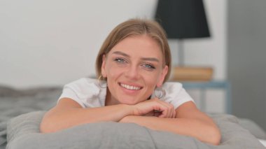 Gülümseyen genç kadın kamera yatakta bakarak yakın çekim
