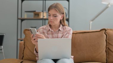 Dışarıda otururken Dizüstü bilgisayar ve akıllı telefon kullanan genç kadın.