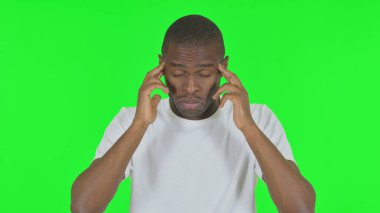 Yeşil arka planda migreni olan Afrikalı adamın portresi