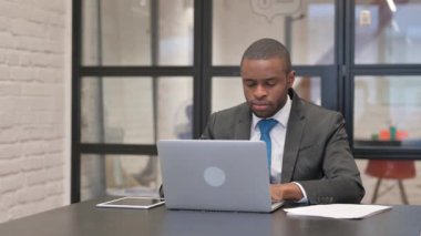 Dizüstü bilgisayar üzerinde çalışırken kameraya bakan Afrikalı İşadamı