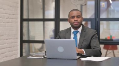 Afrikalı İşadamı Bilgisayarda çalışırken Kameraya Gülümsüyor