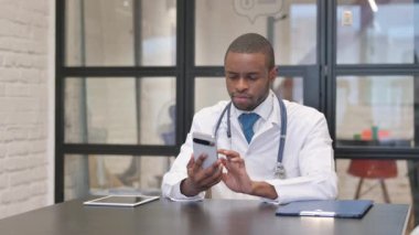 Hastanede akıllı telefon kullanan Afrikalı erkek doktor.