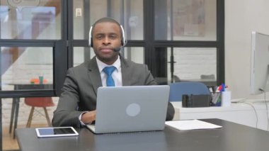 Kulaklıklı Afro-Amerikalı İşadamı Dizüstü bilgisayar kullanarak Başparmağını kaldırdı