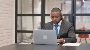 Kulaklıklı Afrikalı İşadamı Dizüstü bilgisayar Kullanarak Başparmağını kaldırdı