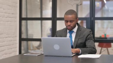 Kulaklıklı Afrikalı İşadamı Ofiste Dizüstü bilgisayarla çalışıyor