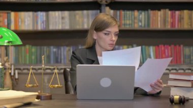Ofisteki dizüstü bilgisayarda evrak işi yapan kadın avukat.