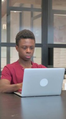 Laptop 'ta çalıştıktan sonra sıradan bir Afrikalı adamın ofisten çıkışının dikey videosu