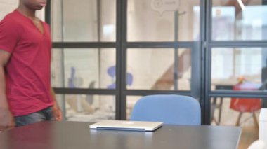 Genç Afrikalı Adam geliyor, işe dizüstü bilgisayar açıyor.