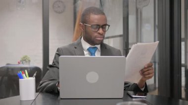 Belgeler ve Dizüstü bilgisayar üzerinde çalışan şoke olmuş Afrikalı İşadamı