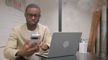 Dizüstü bilgisayarlı Afrikalı Adam Telefonu Kullanıyor