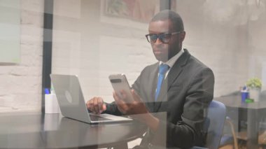 Afrikalı İşadamı Laptop ile Telefonu Kullanıyor