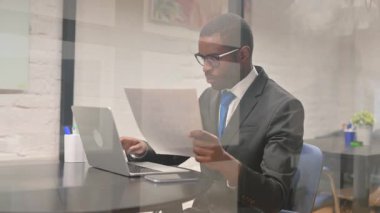 Afrika işadamı belgeleri ve Laptop üzerinde çalışma