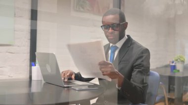 Belgeler ve Dizüstü bilgisayar üzerinde çalışan şoke olmuş Afrikalı İşadamı