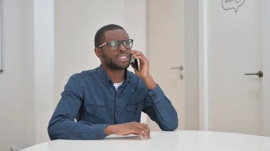 Genç Afrikalı adam müşteriyle telefonda konuşuyor.