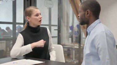 Kızgın Orta yaşlı adam toplantı sırasında bayan meslektaşıyla konuşuyor.