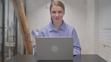 Bilgisayarda çalışırken kamerayı gösteren genç kadın.