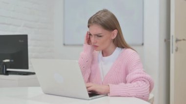 Baş ağrısı olan yaratıcı genç kadın dizüstü bilgisayarda çalışıyor.