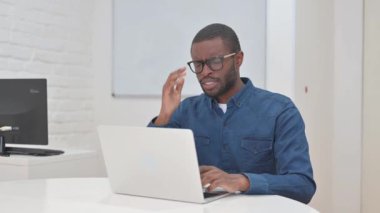 Orta yaşlı, iş yerinde baş ağrısı olan Afrikalı.