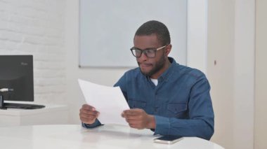 Orta yaşlı Afrikalı Adam Şirketin Yıllık İş Raporunu Okuyor