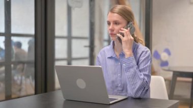Genç kadın konuşurken Laptop üzerinde çalışma sırasında telefon