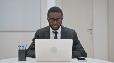 Gülümseyen Afrikalı Amerikalı işadamı ofisteyken kameraya özgüvenle bakıyor.