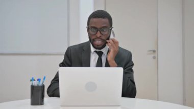 Profesyonel Afro-Amerikan işadamı acil bir telefon görüşmesi yaptı, bilgisayarına odaklandı.