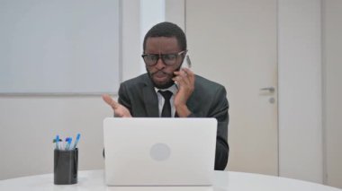 Sıkıntılı bir Afrikalı Amerikalı işadamı yoğun bir telefon görüşmesi yaptı. Dizüstü bilgisayarında çalışırken hayal kırıklığını dile getirdi.