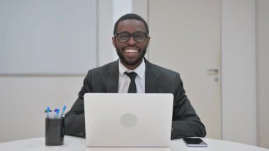 Takım elbiseli Afro-Amerikan bir işadamı, bir ofis ortamında açık ağızlı ve geniş gözlü bir ifadeyle doğrudan izleyiciyi işaret ediyor.