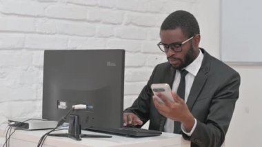 İşadamı Masaüstü Bilgisayarı ile Akıllı Telefon Kullanıyor