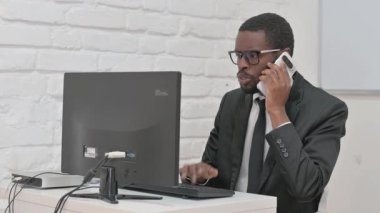 İş Adamı Telefonda Konuşuyor ve Bilgisayarda Çalışıyor