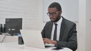 Gülümseyen Afrikalı Amerikalı işadamı ofisteyken kameraya özgüvenle bakıyor.