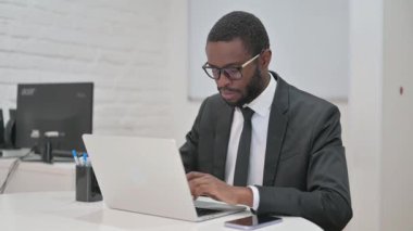 Ürkmüş Afrikalı Amerikalı iş adamı kameraya bakarken şaşkın şaşkın bakıyor.