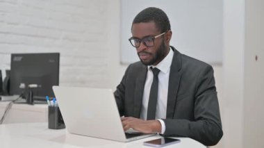 Onaylamayan Afro-Amerikan iş adamı ofis masasından olumlu bir jest yapıyor.