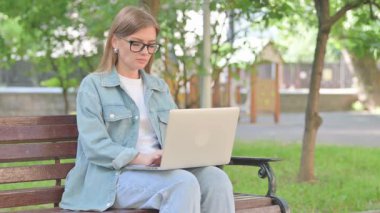 Park Bench 'te dizüstü bilgisayarı olan stresli genç kadın.
