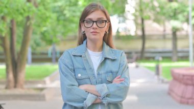 Kolları çaprazlanmış, gülümseyen genç kadın.