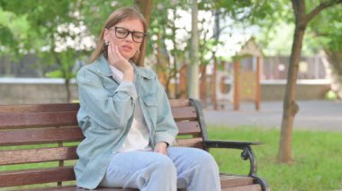 Park Bench 'inde diş ağrısı olan rahatsız bir genç kadın.